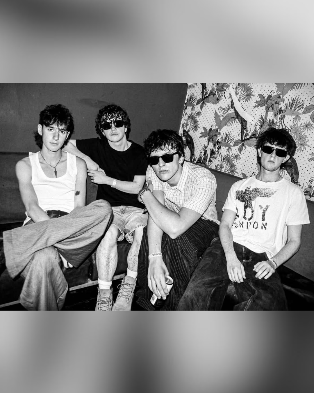 Willows band portrait, four young men on a sofa in front of tropical wallpaper